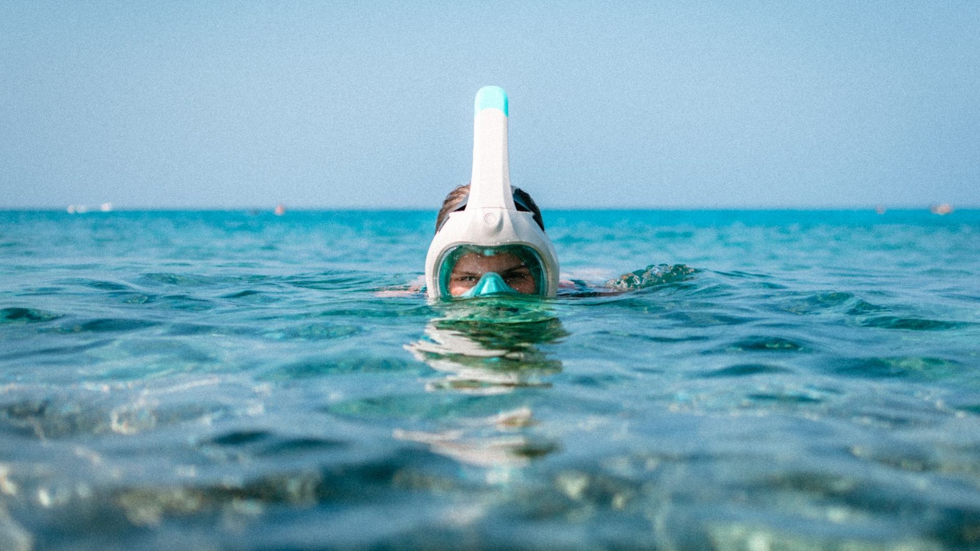 Turista con maschera e pinne fa snorkeling in acque cristalline della Sardegna